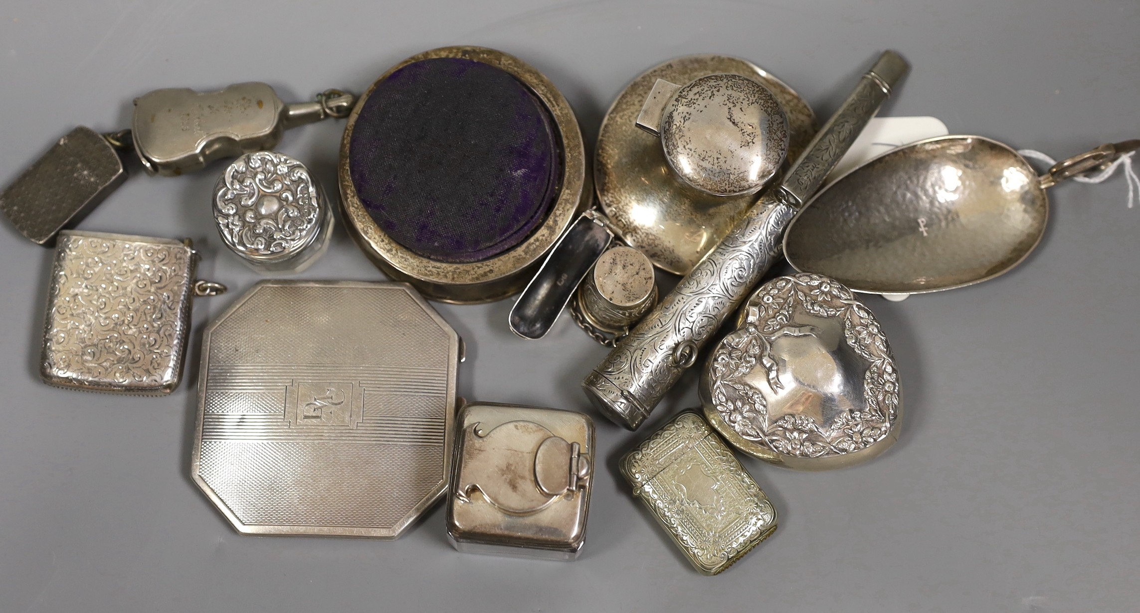 A group of assorted small silver and other items including plated violin vesta case, silver mounted pin cushion, silver heart shaped box, cigarette case, inkwells, planished spoon etc.